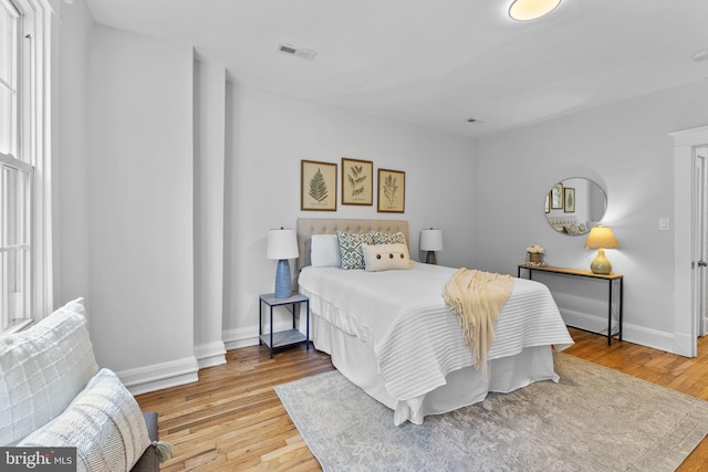 bedroom featuring light wood finished floors, visible vents, and baseboards