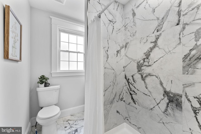 bathroom featuring marble finish floor, a stall shower, toilet, and baseboards