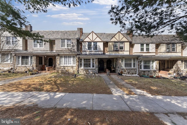 view of front facade featuring stone siding, stucco siding, a porch, and a chimney