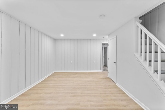 finished basement with stairs, recessed lighting, light wood-style floors, and baseboards