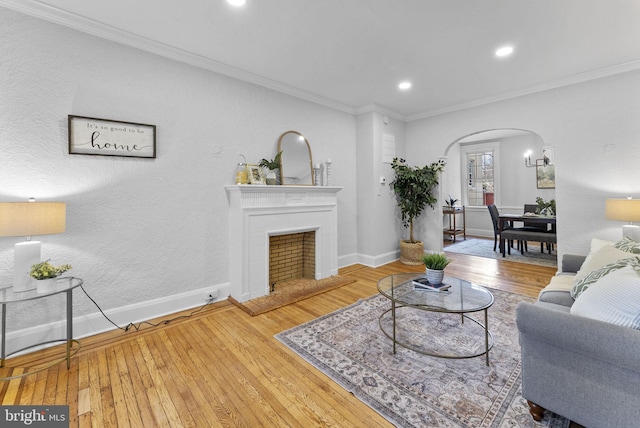 living room with baseboards, arched walkways, hardwood / wood-style floors, and ornamental molding