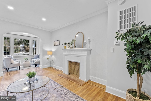 living room with arched walkways, crown molding, baseboards, and wood finished floors