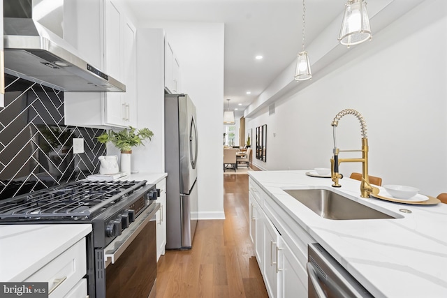 kitchen with range hood, stainless steel appliances, light wood-style flooring, white cabinets, and a sink