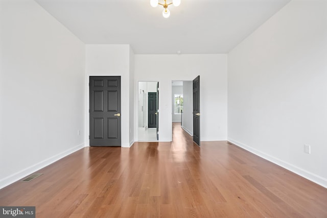 unfurnished room with wood finished floors, visible vents, and baseboards