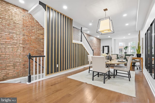 dining room with brick wall, stairway, wood finished floors, and recessed lighting