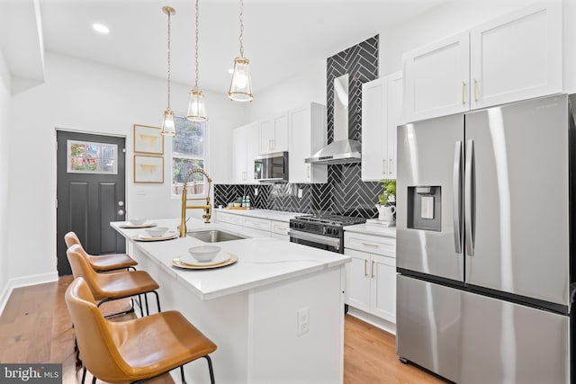 kitchen featuring a breakfast bar area, stainless steel appliances, a sink, white cabinets, and an island with sink