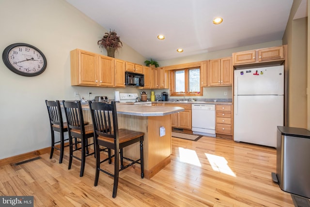 kitchen with white appliances, visible vents, a peninsula, and light wood finished floors