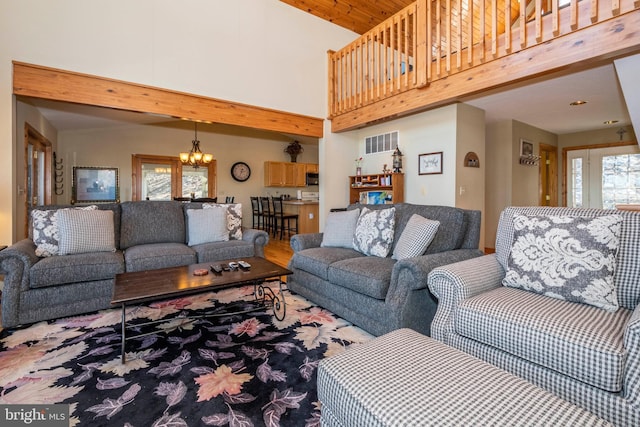 living room with a chandelier, wood finished floors, a towering ceiling, and visible vents