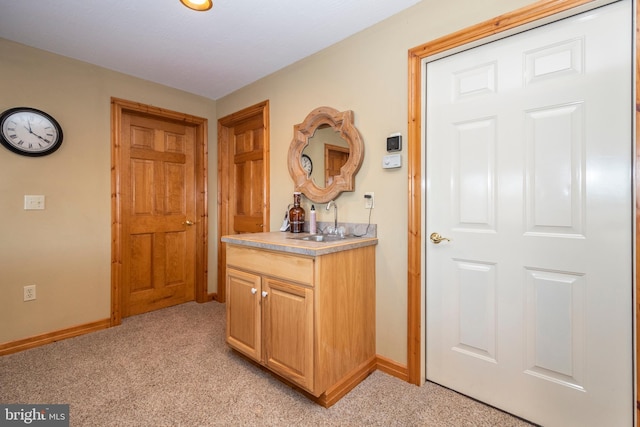 interior space featuring light colored carpet, a sink, and baseboards