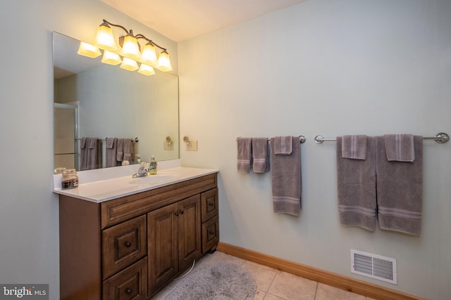 bathroom featuring visible vents, a shower with shower door, vanity, baseboards, and tile patterned floors