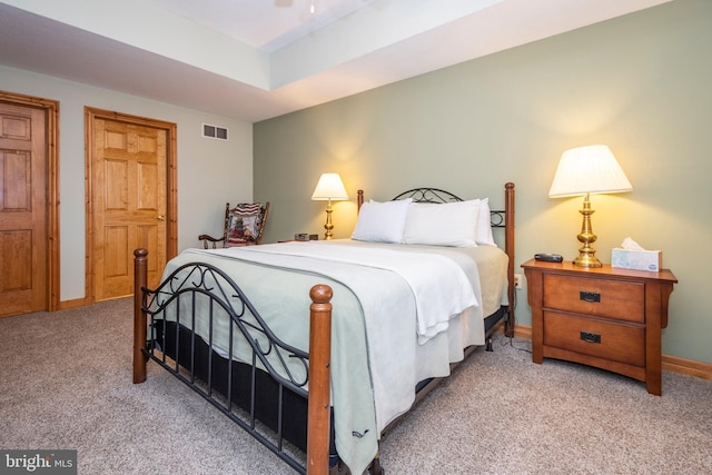 carpeted bedroom with baseboards, visible vents, and a tray ceiling