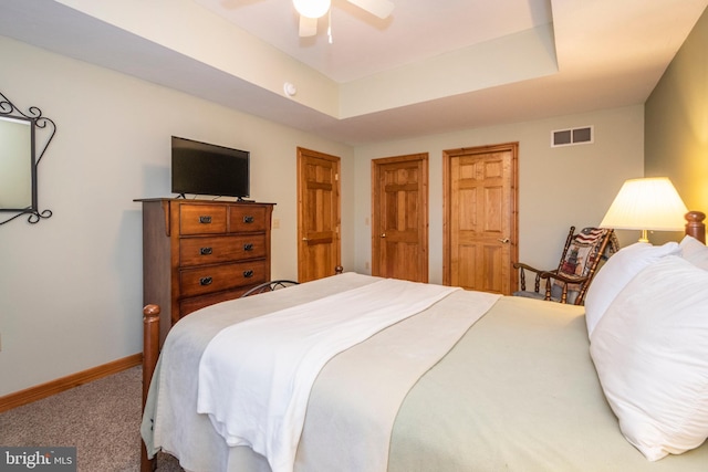 bedroom featuring ceiling fan, carpet flooring, visible vents, baseboards, and a tray ceiling