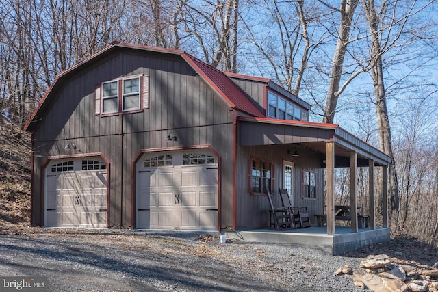 view of front of property with a garage, covered porch, metal roof, and a gambrel roof