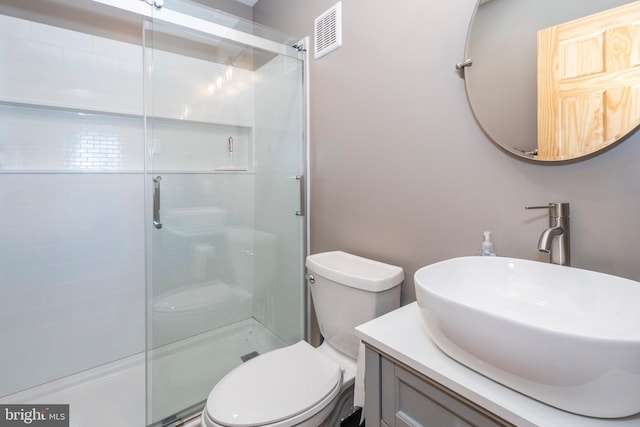 bathroom featuring toilet, a shower with door, and visible vents