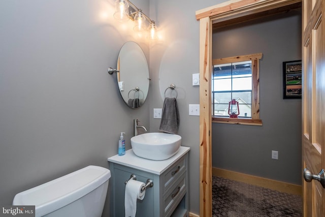 bathroom featuring toilet, vanity, and baseboards