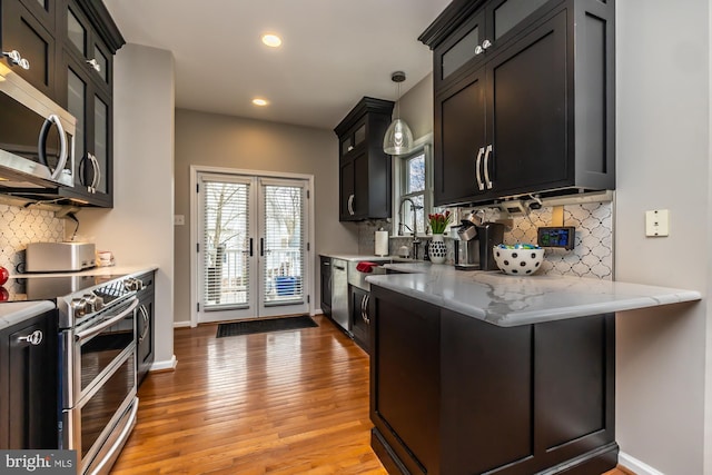 kitchen with light stone counters, light wood-type flooring, baseboards, and appliances with stainless steel finishes