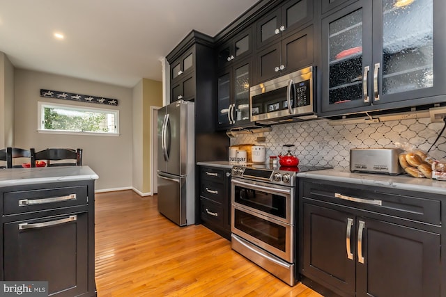 kitchen featuring light countertops, dark cabinets, backsplash, and stainless steel appliances