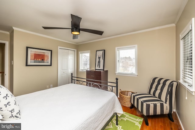 bedroom featuring crown molding, wood finished floors, a closet, and baseboards