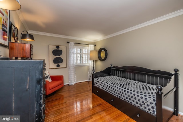 bedroom featuring wood finished floors, baseboards, and ornamental molding