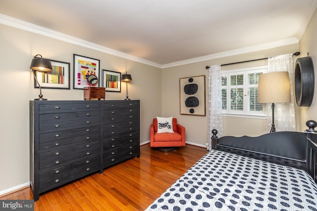 bedroom featuring baseboards, wood finished floors, and crown molding