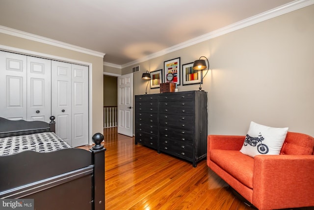 bedroom with a closet, visible vents, ornamental molding, and wood finished floors