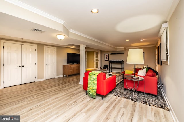 living area with visible vents, wood finished floors, baseboards, and ornamental molding