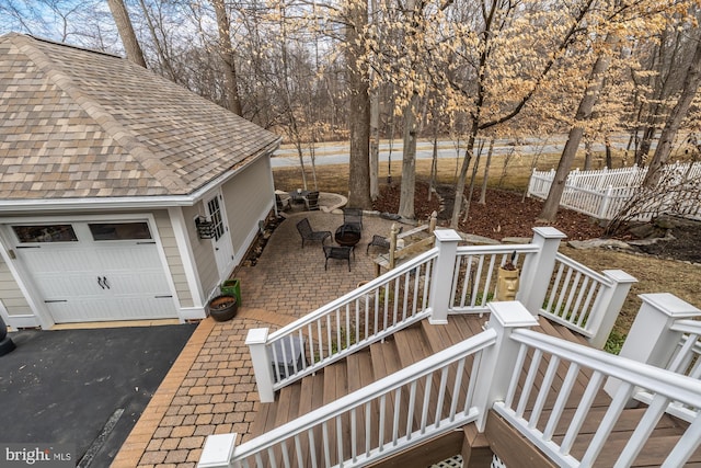 wooden deck featuring fence, stairway, a garage, a patio area, and driveway