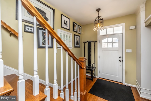 entrance foyer featuring stairway, baseboards, a notable chandelier, and wood finished floors