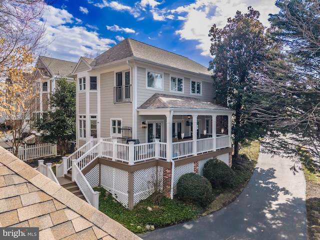 rear view of property with a shingled roof, stairs, and fence