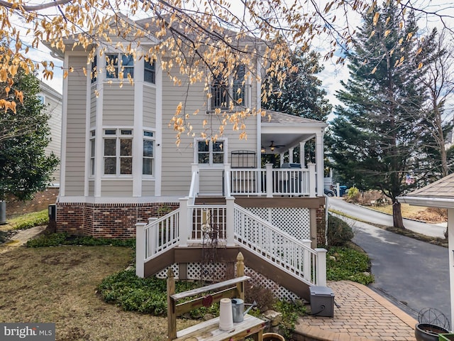 rear view of house with stairway, brick siding, covered porch, and ceiling fan