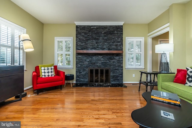 living area featuring a fireplace, baseboards, and wood finished floors