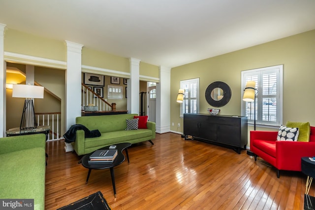 living area with stairs, ornate columns, and hardwood / wood-style flooring