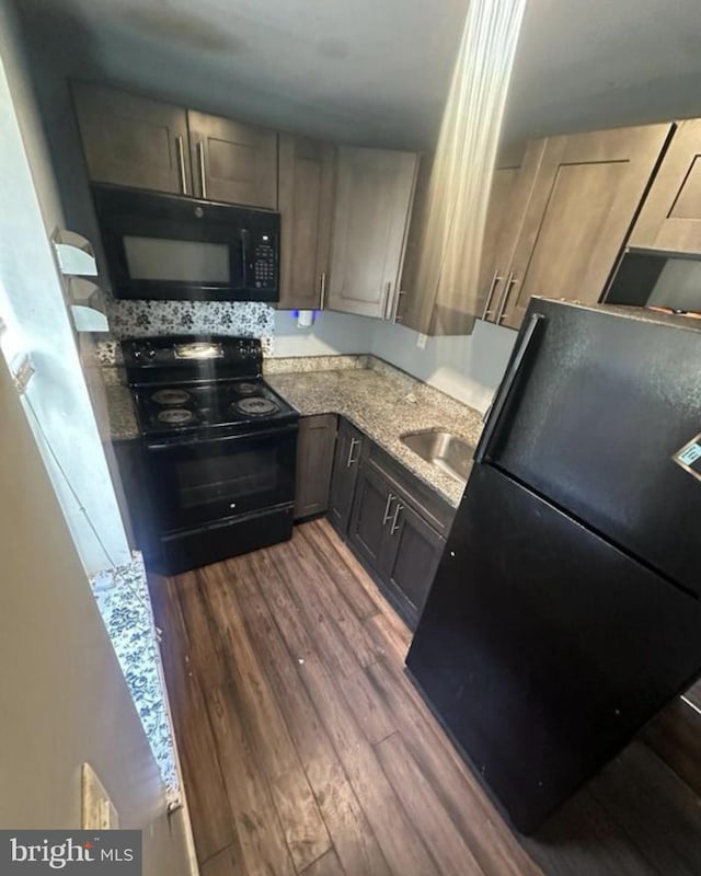 2837 Stouton St, Philadelphia, PA 19134 - kitchen featuring a sink, light stone countertops, black appliances, and dark wood-type flooring