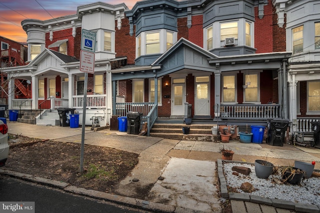 multi unit property featuring a porch and brick siding