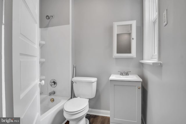 bathroom featuring vanity, wood finished floors, baseboards, tub / shower combination, and toilet