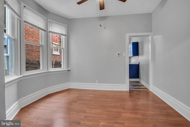 empty room featuring wood finished floors, a ceiling fan, and baseboards