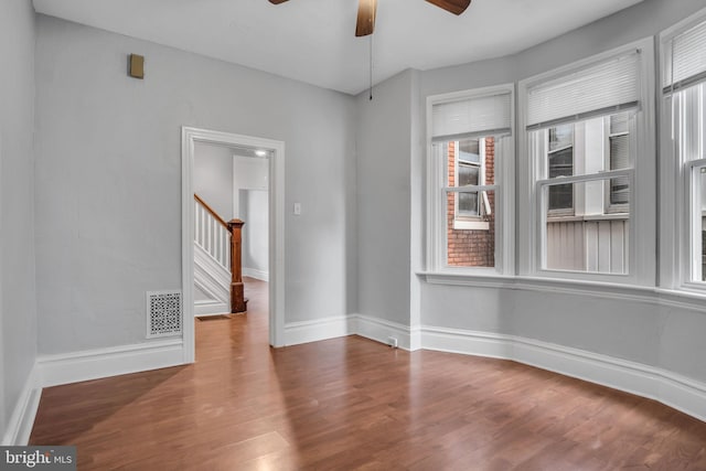 unfurnished room with a wealth of natural light, visible vents, wood finished floors, and ceiling fan