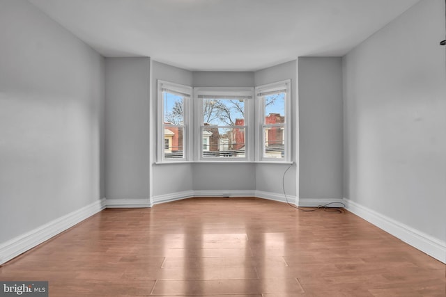 spare room featuring baseboards and wood finished floors