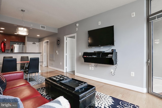 living area with light wood finished floors, baseboards, and visible vents