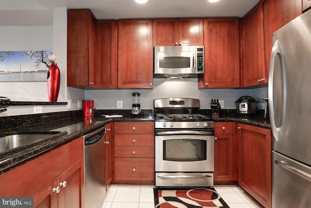 kitchen featuring dark stone counters, stainless steel appliances, and light tile patterned flooring