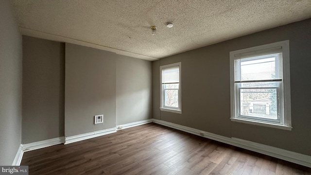 spare room with baseboards, dark wood finished floors, and a textured ceiling