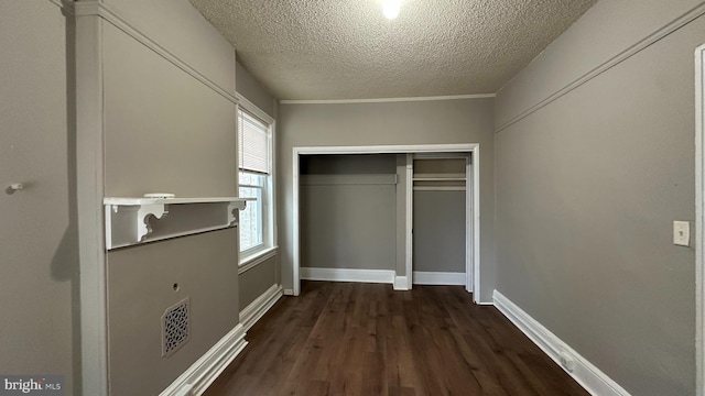 unfurnished bedroom with baseboards, visible vents, dark wood-style floors, a textured ceiling, and a closet