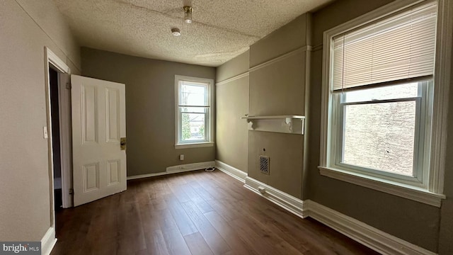 interior space featuring dark wood-style floors, a textured ceiling, and baseboards