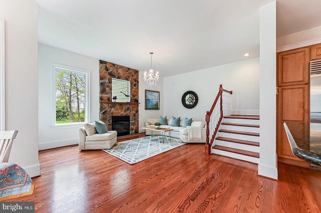 living area with baseboards, wood finished floors, stairs, a fireplace, and a chandelier