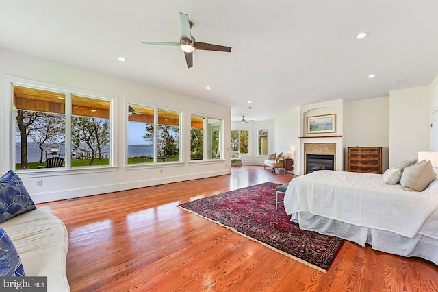 bedroom with ceiling fan, recessed lighting, wood finished floors, baseboards, and a glass covered fireplace