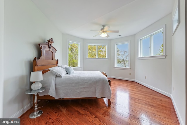 bedroom featuring visible vents, baseboards, ceiling fan, and wood finished floors