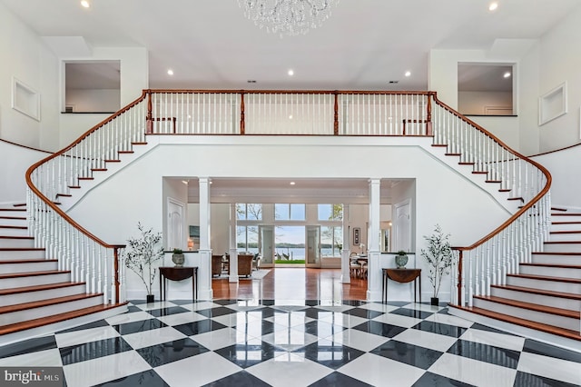 entrance foyer with decorative columns, a high ceiling, stairway, and baseboards