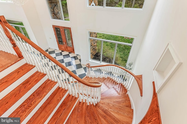 stairway featuring a towering ceiling, a notable chandelier, and tile patterned floors