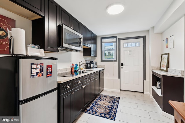 kitchen with dark cabinetry, light tile patterned floors, baseboards, and stainless steel appliances