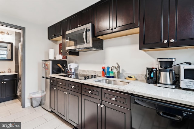 kitchen featuring light stone counters, light tile patterned floors, black appliances, and a sink